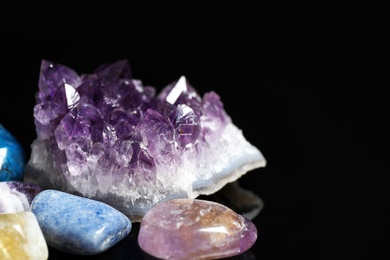 Photo of Different beautiful gemstones on black background, closeup. Space for text