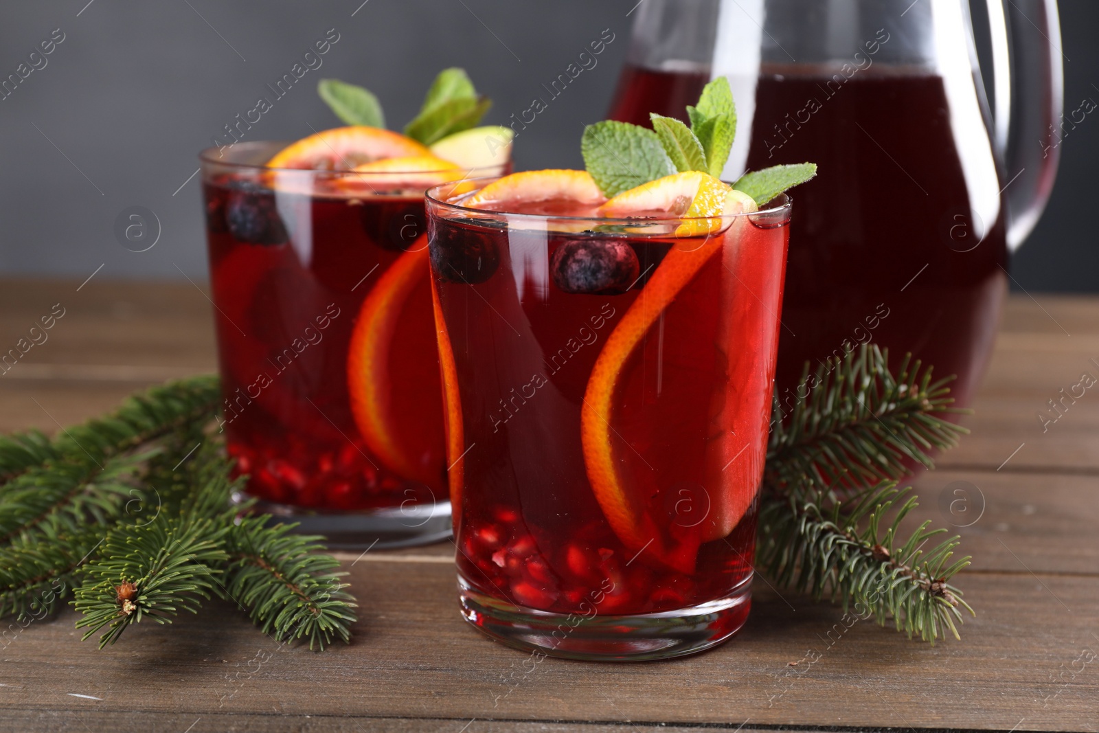 Photo of Aromatic Christmas Sangria drink and fir branches on wooden table