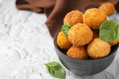 Photo of Bowl of delicious fried tofu balls with basil on white textured table, closeup. Space for text