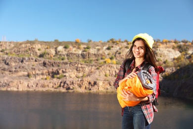 Photo of Female camper with sleeping bag near beautiful lake. Space for text