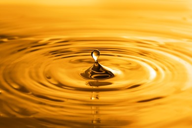 Image of Splash of golden oily liquid with drop as background, closeup