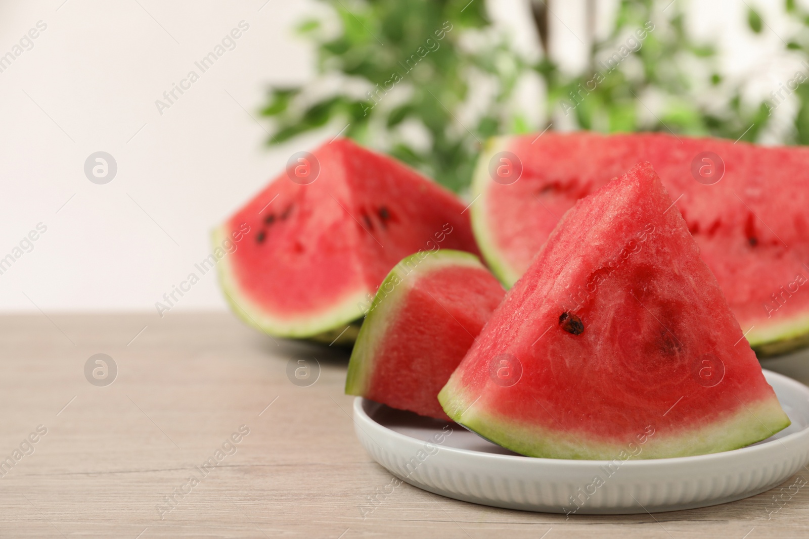 Photo of Slices of tasty ripe watermelon on light wooden table, space for text