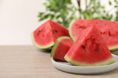 Photo of Slices of tasty ripe watermelon on light wooden table, space for text