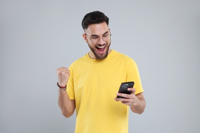 Photo of Happy young man using smartphone on grey background