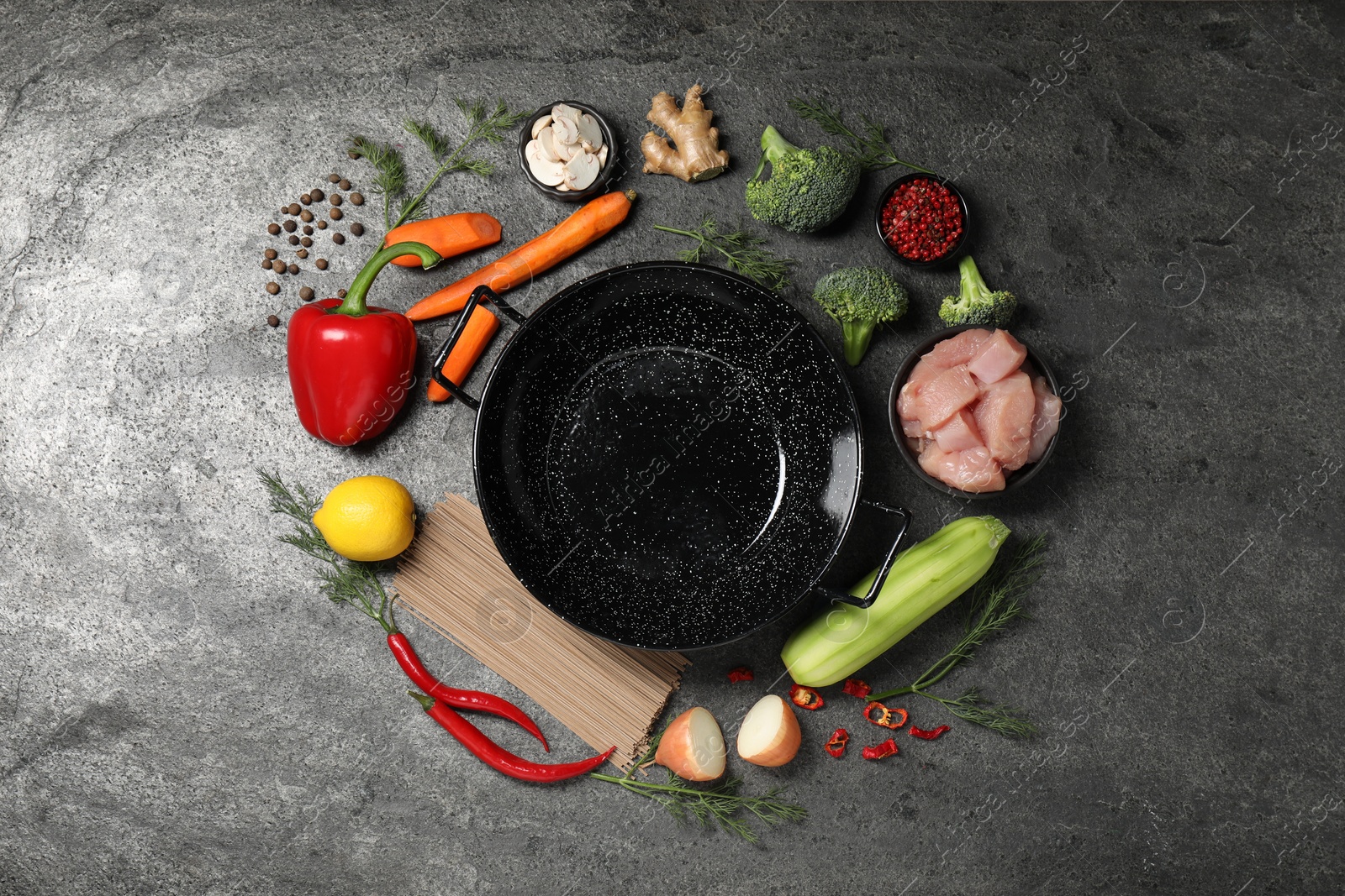 Photo of Empty iron wok surrounded by ingredients on grey table, flat lay