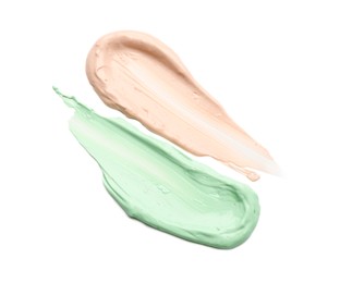 Photo of Strokes of pink and green color correcting concealers isolated on white, top view