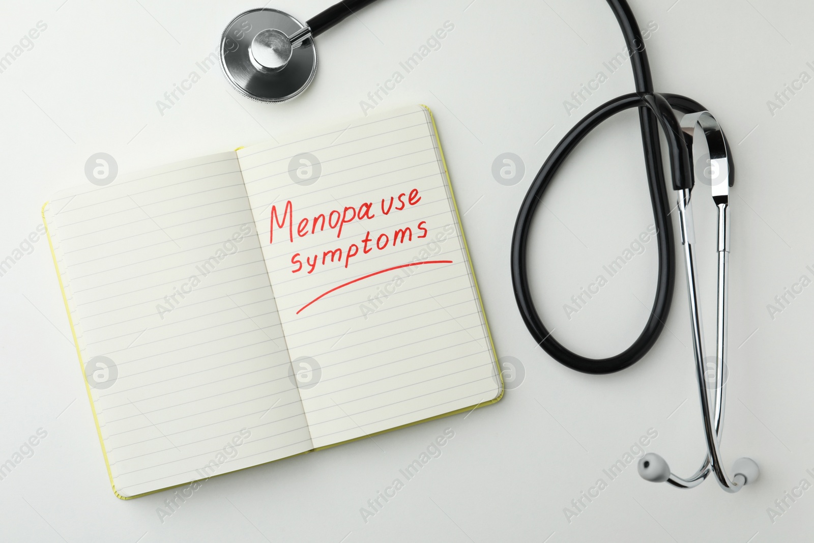 Photo of Notebook with words Menopause Symptoms and stethoscope on white table, flat lay