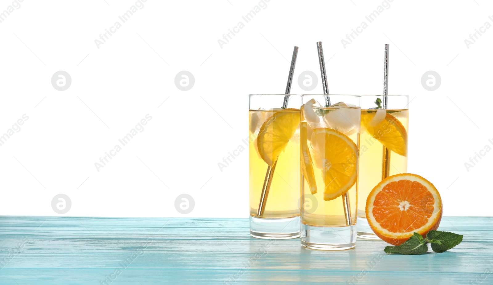 Photo of Delicious refreshing drink with orange slices on light blue wooden table against white background. Space for text