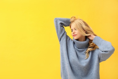 Beautiful young woman wearing warm blue sweater on yellow background. Space for text