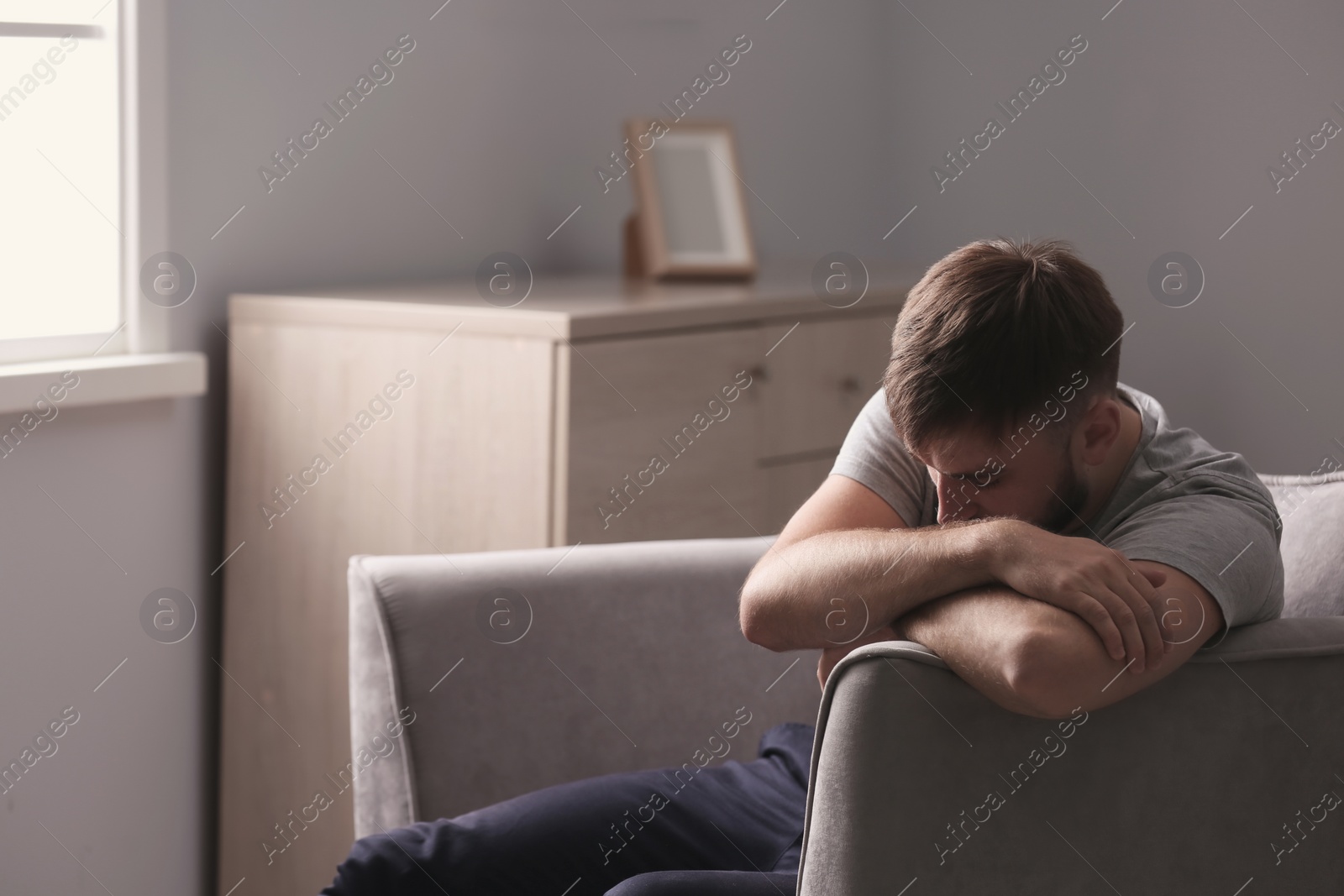 Photo of Depressed young man sitting in armchair at home