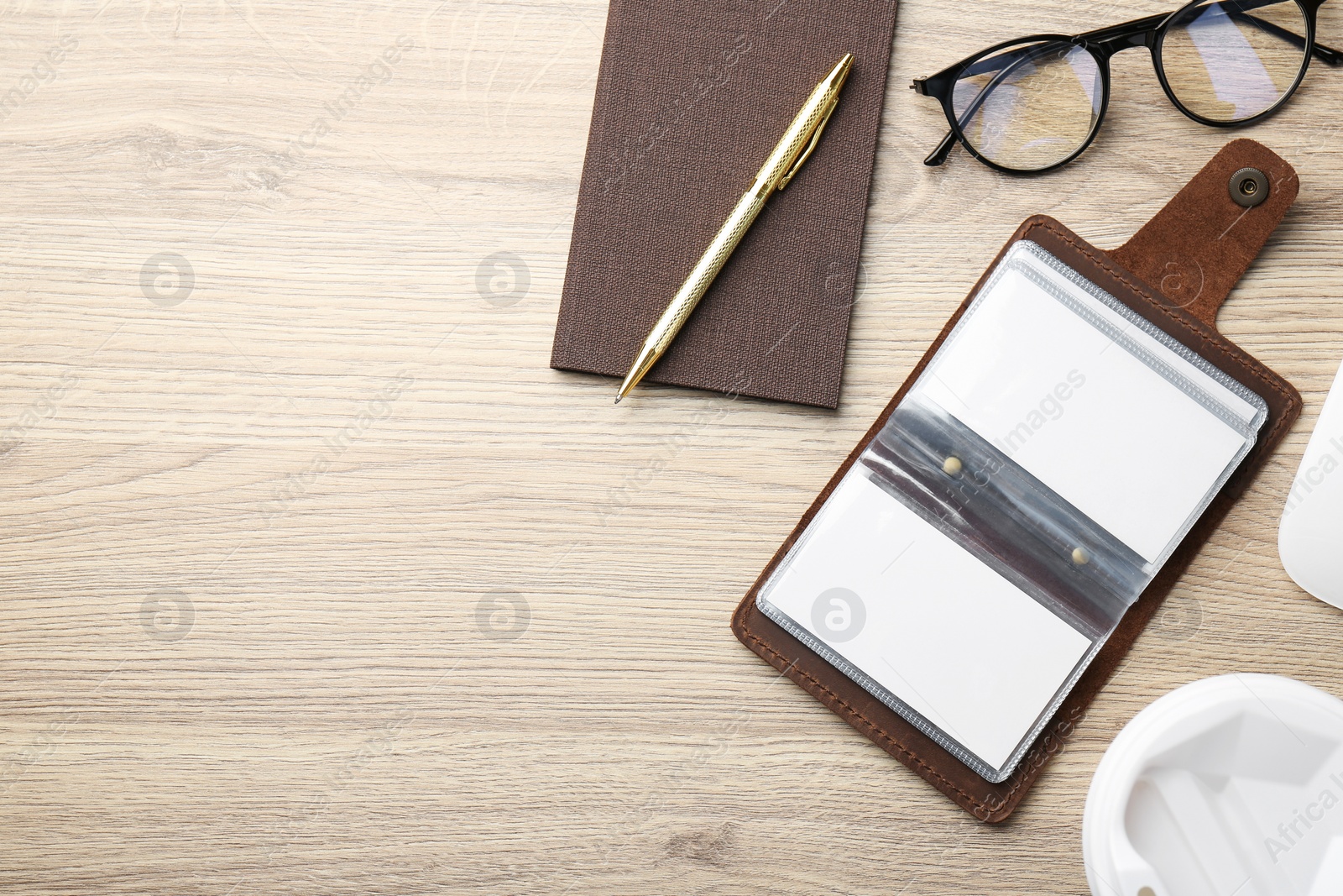 Photo of Leather business card holder with blank cards, stationery and glasses on wooden table, flat lay. Space for text