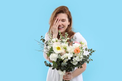 Photo of Beautiful woman with bouquet of flowers on light blue background