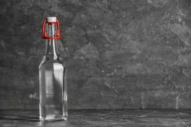 Photo of Glass bottle with vinegar on grey background. Space for text