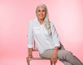 Portrait of beautiful mature woman on pink background, space for text