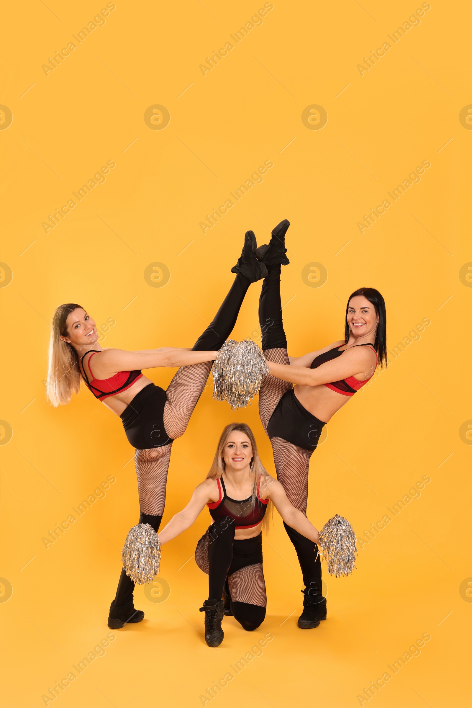 Photo of Group of beautiful cheerleaders on yellow background