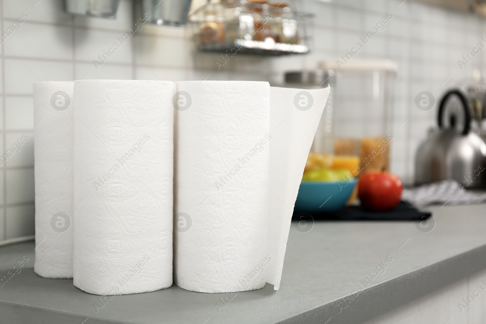 Photo of Rolls of paper towels on table in kitchen, space for text