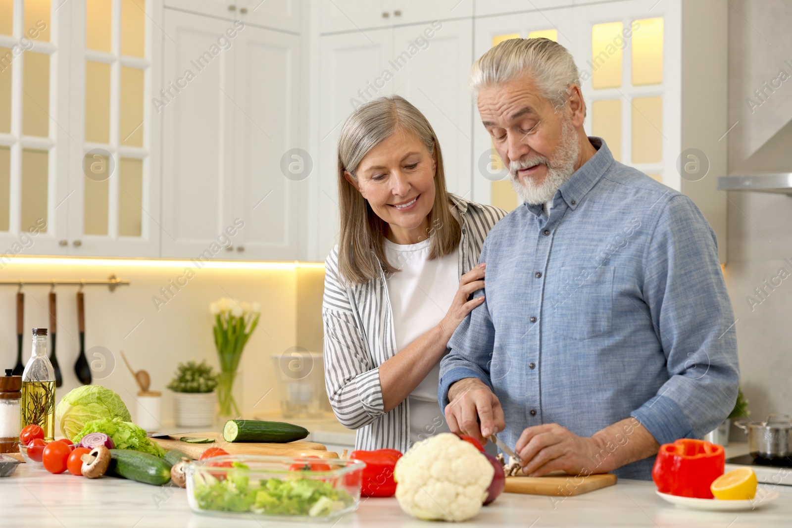 Photo of Happy senior couple cooking together in kitchen