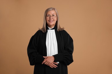Smiling senior judge in court dress on light brown background