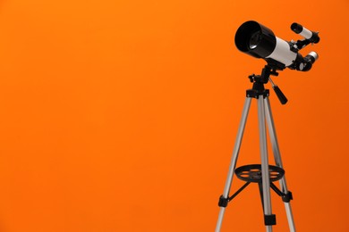 Tripod with modern telescope on orange background. Space for text