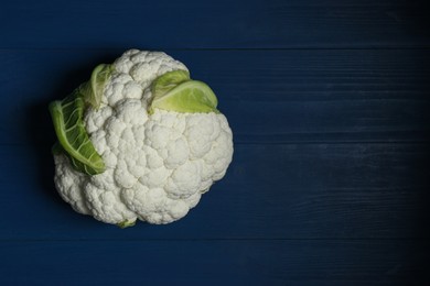 Photo of Fresh whole cauliflower on blue wooden table, top view. Space for text