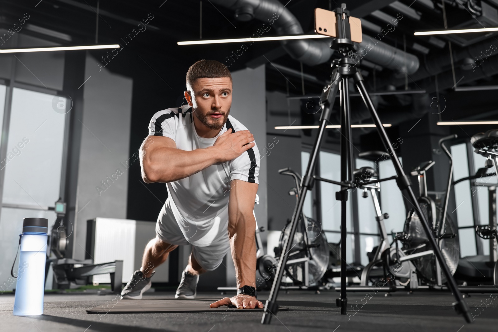 Photo of Trainer streaming online workout with phone at gym