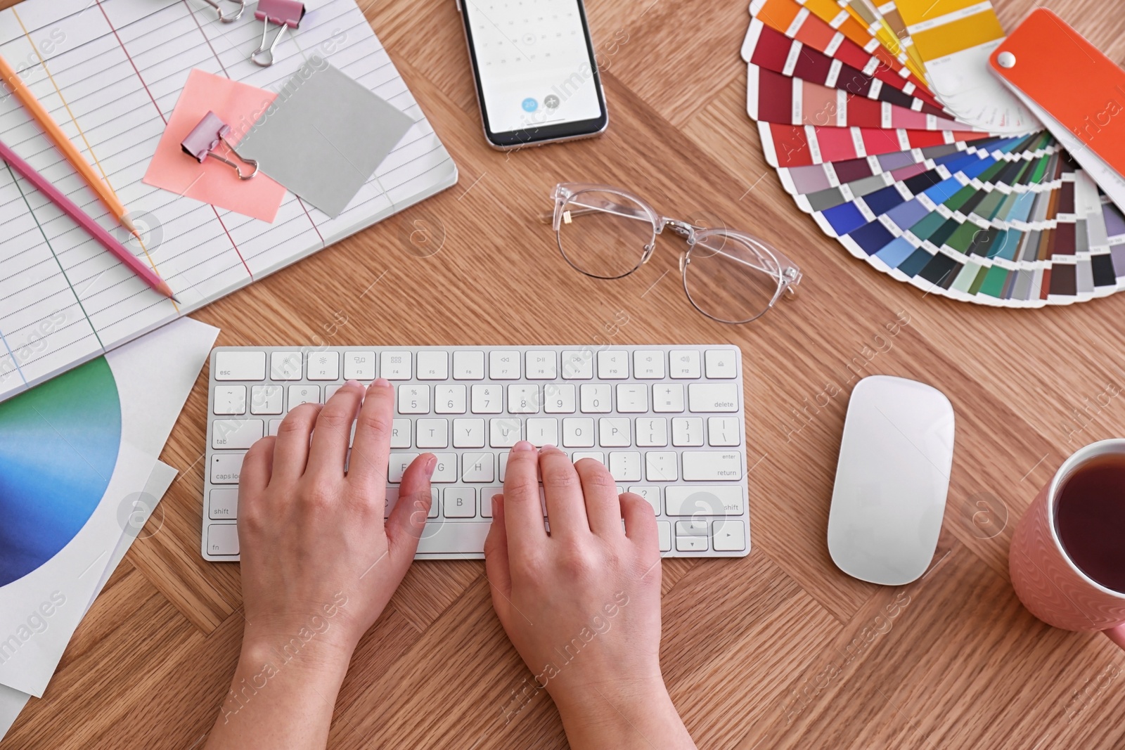 Photo of Designer working on computer at wooden table, top view