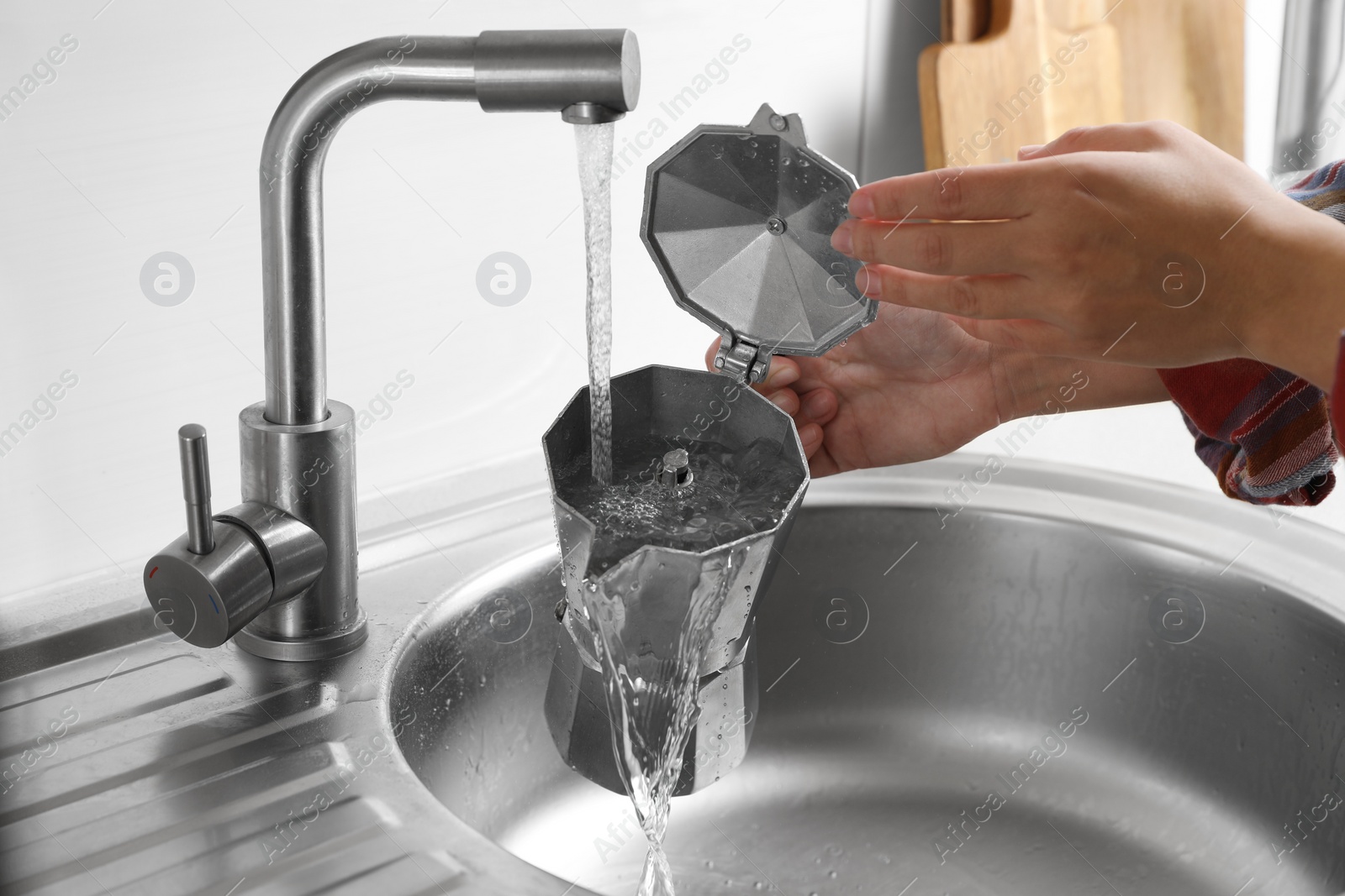 Photo of Woman washing moka pot (coffee maker) above sink in kitchen, closeup