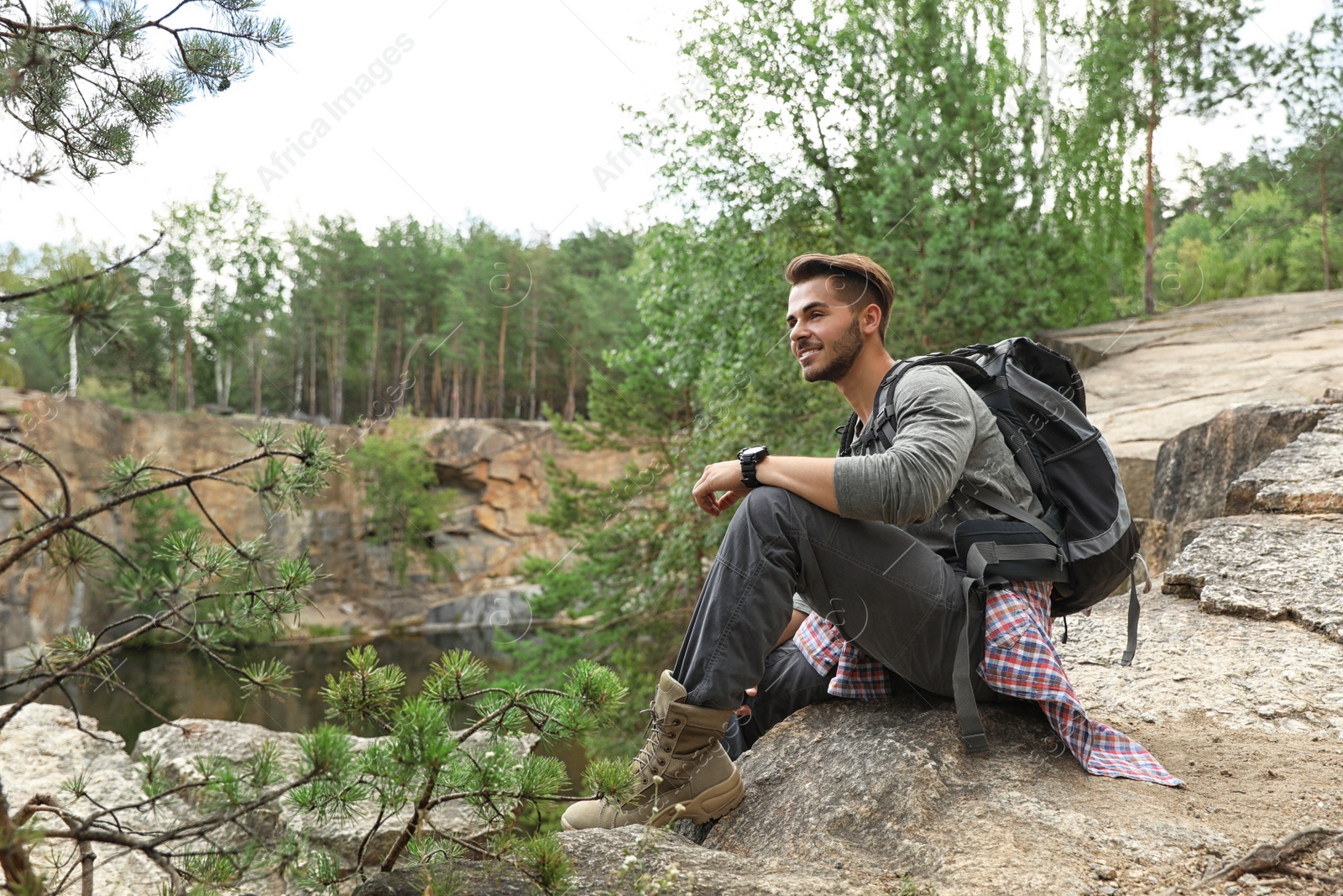 Photo of Young man on rocky mountain near forest. Camping season