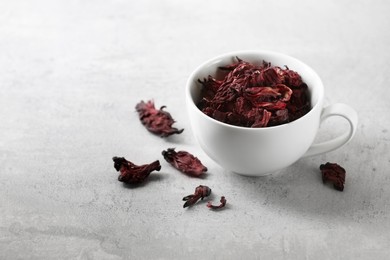 Aromatic hibiscus tea. Dried roselle calyces in cup on light table, space for text