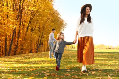 Photo of Happy woman with little daughter walking in autumn park