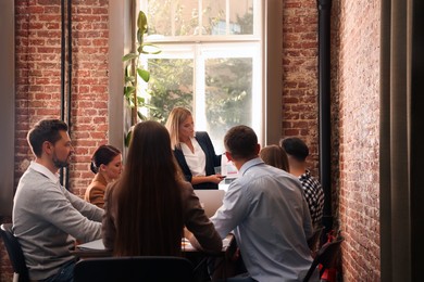 Photo of Businesswoman having meeting with her employees in office. Lady boss