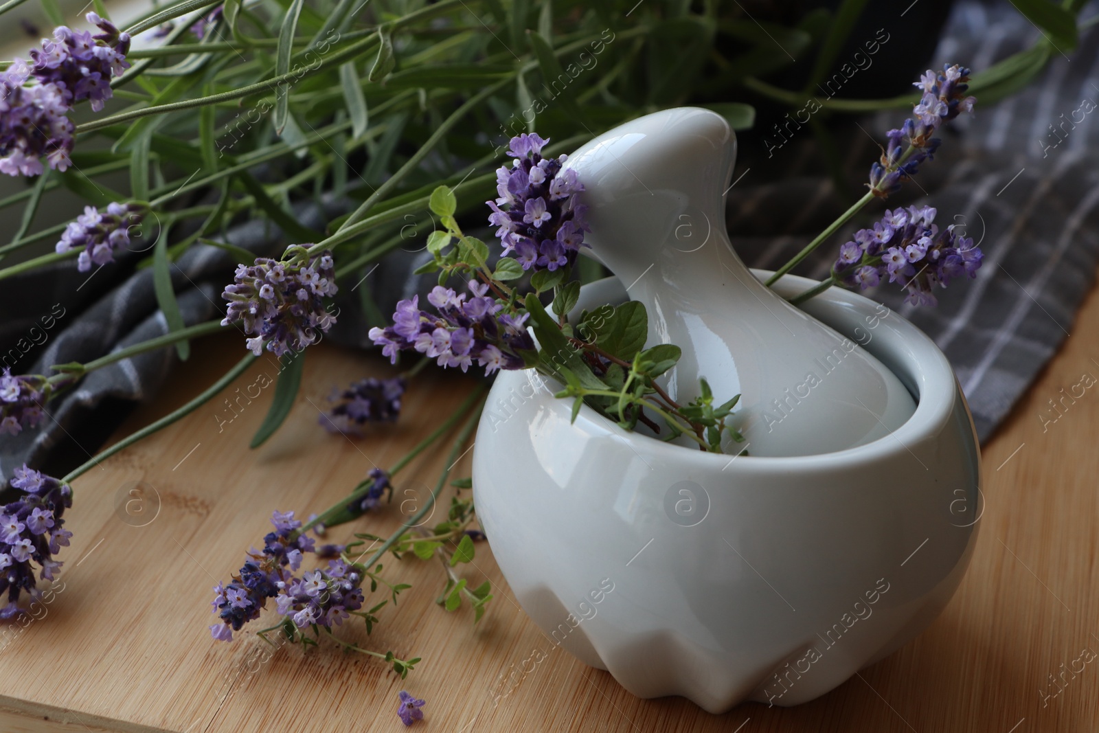 Photo of Mortar with fresh lavender flowers, green twigs and pestle on wooden table