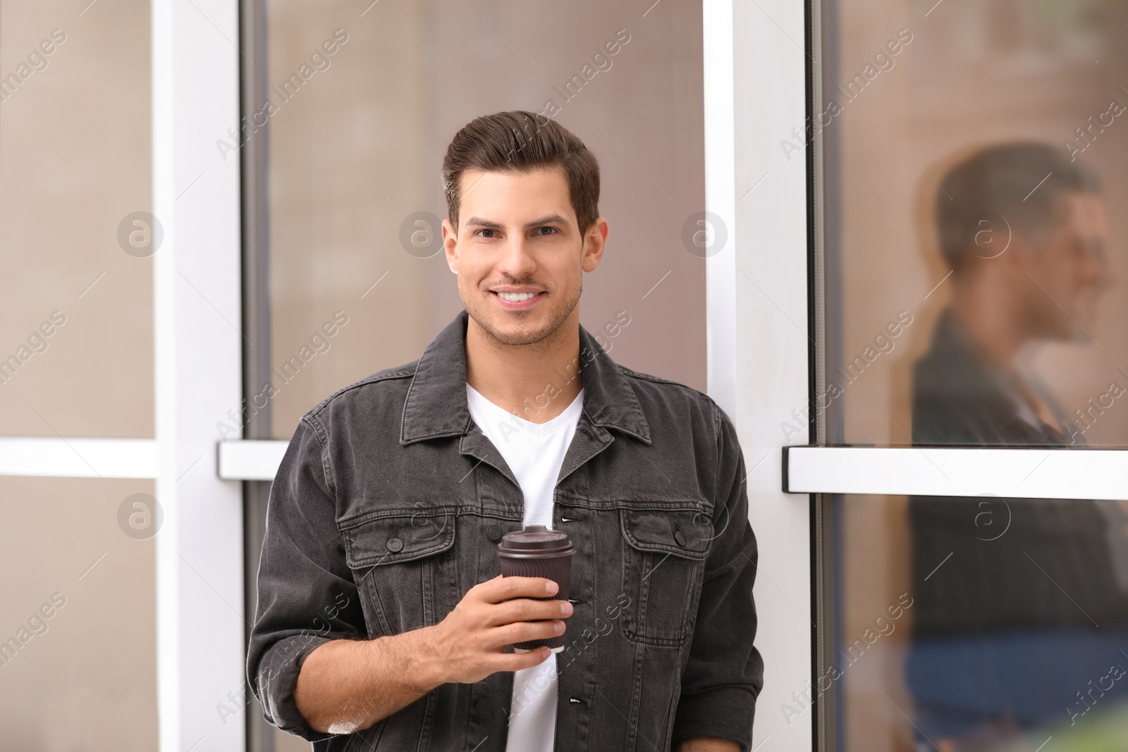 Photo of Handsome man with cup of coffee near window