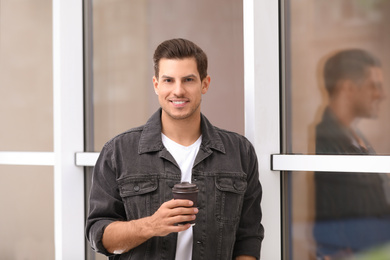 Handsome man with cup of coffee near window