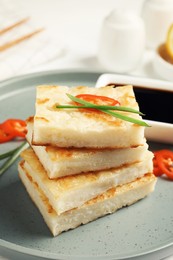 Photo of Delicious turnip cake with chili pepper and green onion on plate, closeup