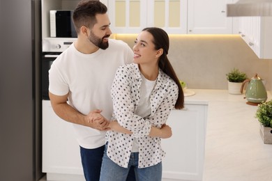 Happy lovely couple dancing together in kitchen