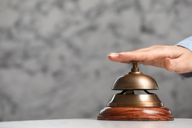 Photo of Woman ringing hotel service bell on grey background. Space for text