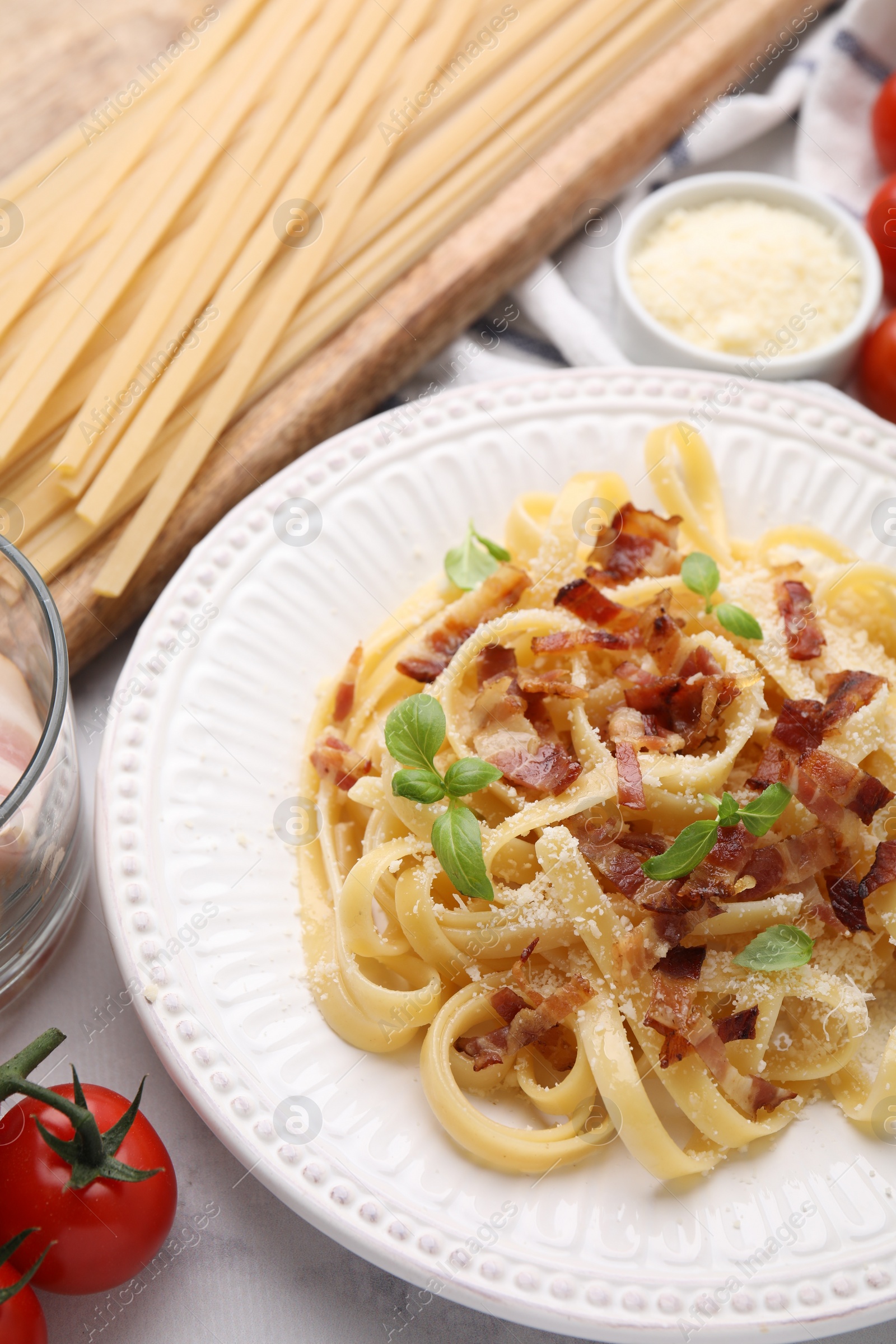 Photo of Tasty pasta with bacon and basil on white marble table