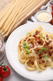 Photo of Tasty pasta with bacon and basil on white marble table