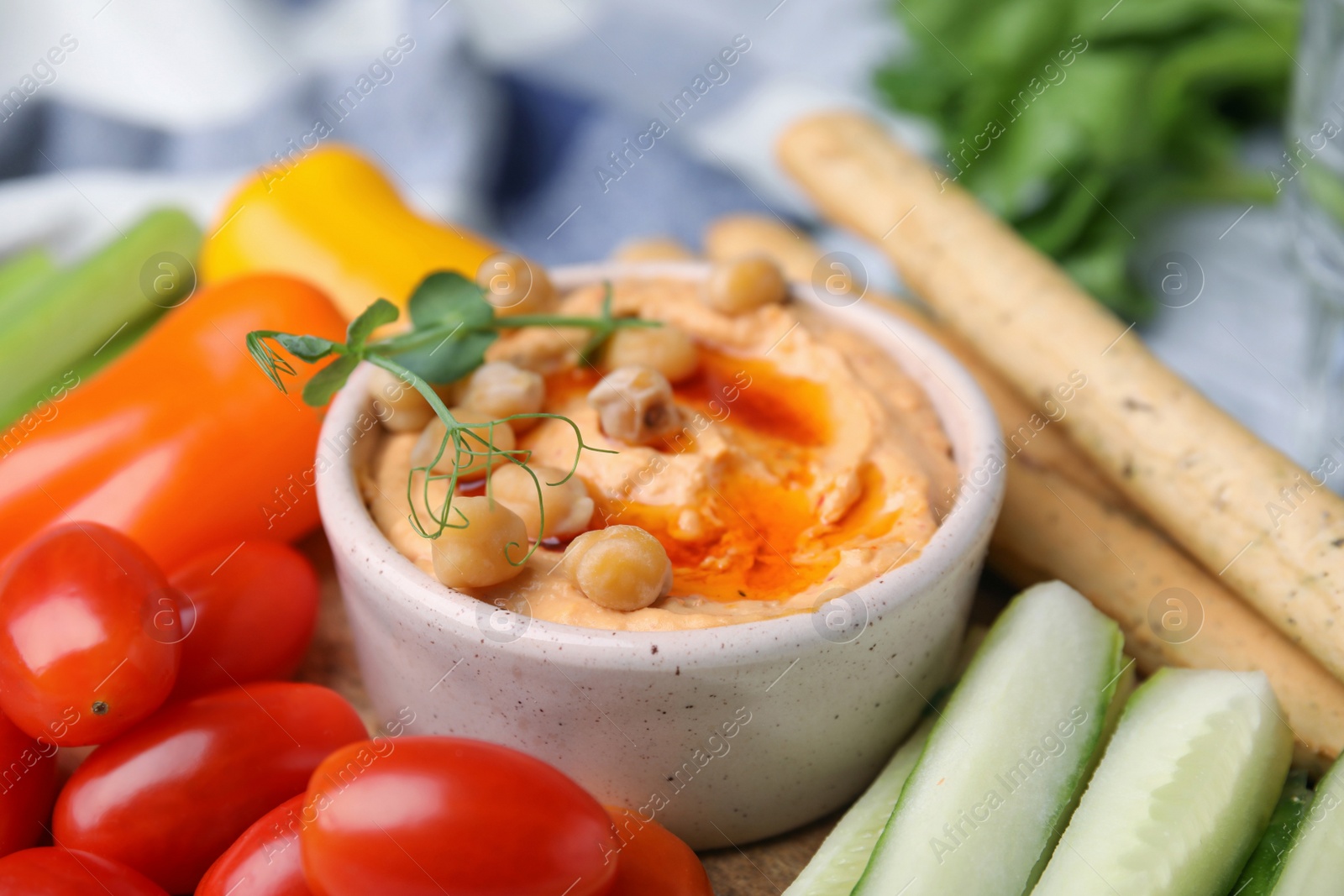 Photo of Board with delicious hummus, grissini sticks and fresh vegetables, closeup