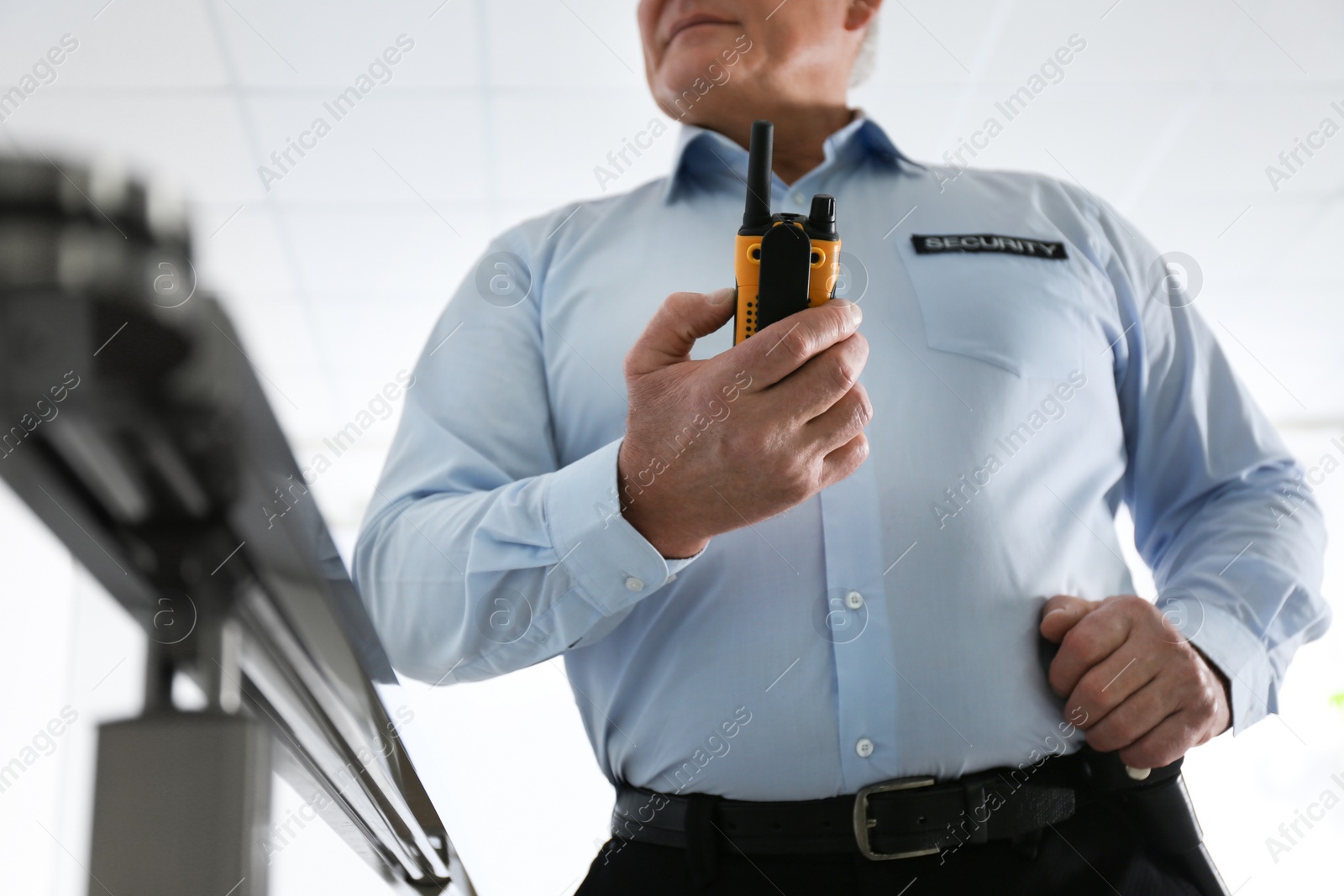 Photo of Professional security guard with portable radio set indoors, closeup