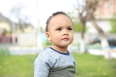 Cute African-American baby in stylish clothes posing outdoors