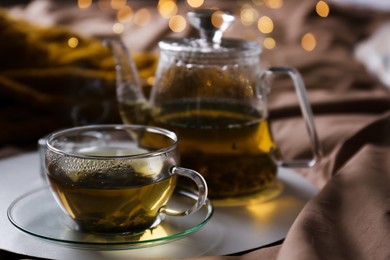 Tray with cup of hot tea and teapot on bed