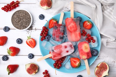 Flat lay composition with fruit and berry ice pops on white wooden table