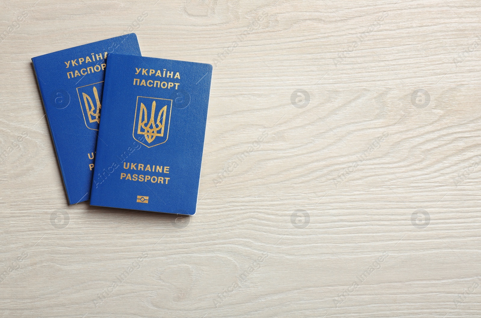 Photo of Ukrainian travel passports on wooden background, top view with space for text. International relationships