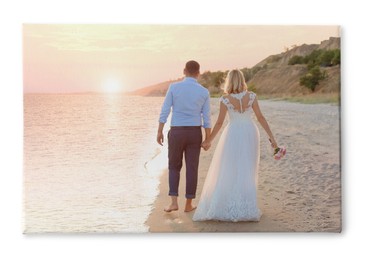 Photo printed on canvas, white background. Bride and groom walking at sunset on beach
