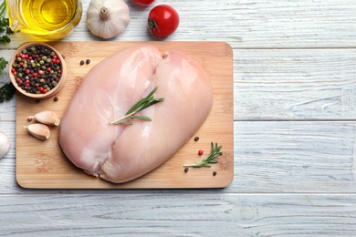 Flat lay composition with raw chicken breasts and ingredients on wooden background. Space for text