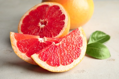 Photo of Fresh tasty grapefruits and leaves on table