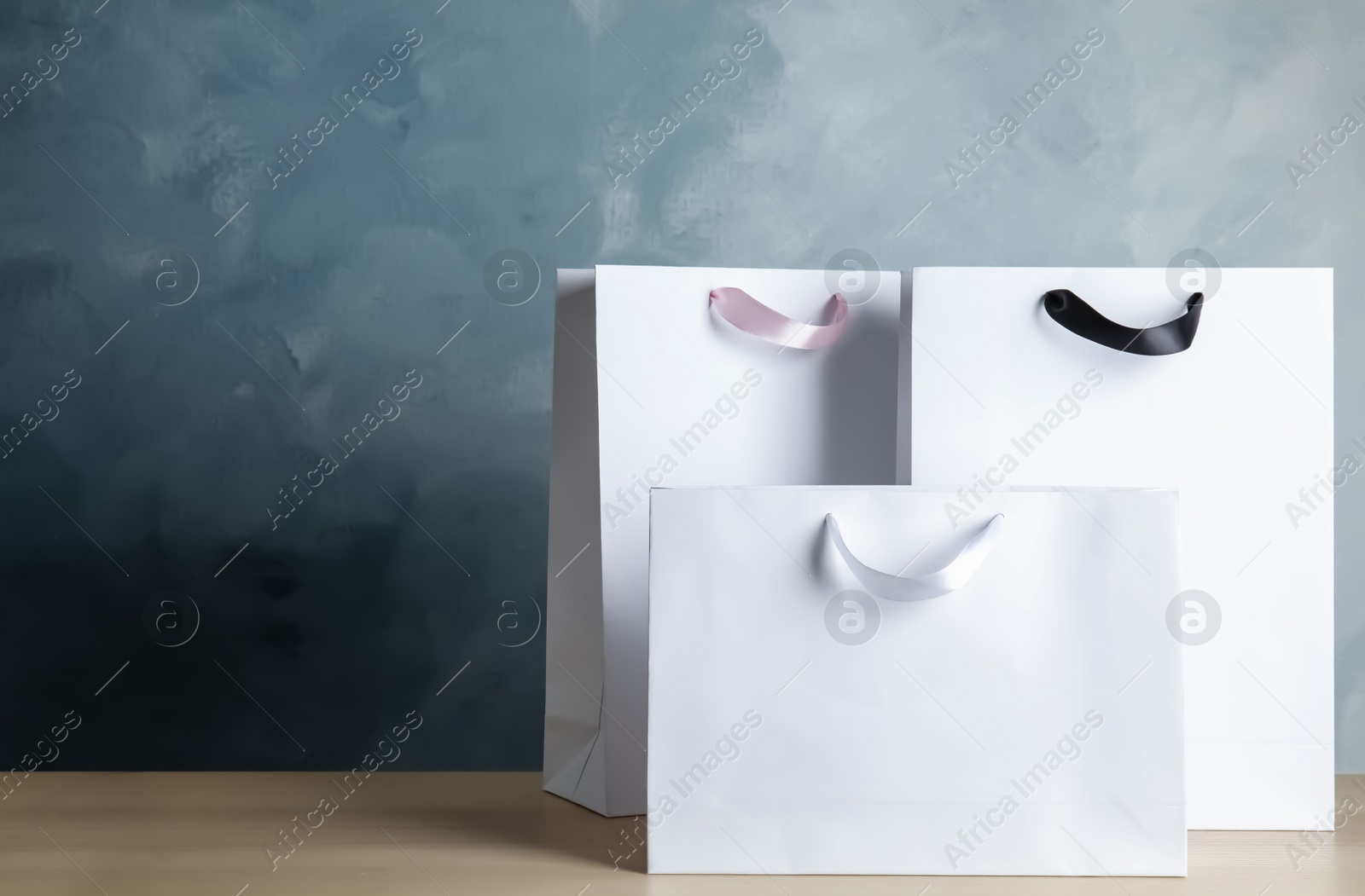 Photo of Paper shopping bags on table against color background. Mock up for design