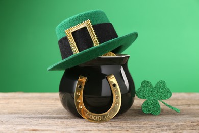 St. Patrick's day. Pot of gold with leprechaun hat, horseshoe and decorative clover leaf on wooden table